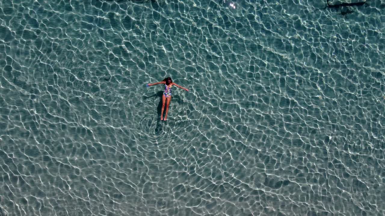 Aerial Top View over a Woman Relaxing and Enjoying Crystal Clear Waters, Paros