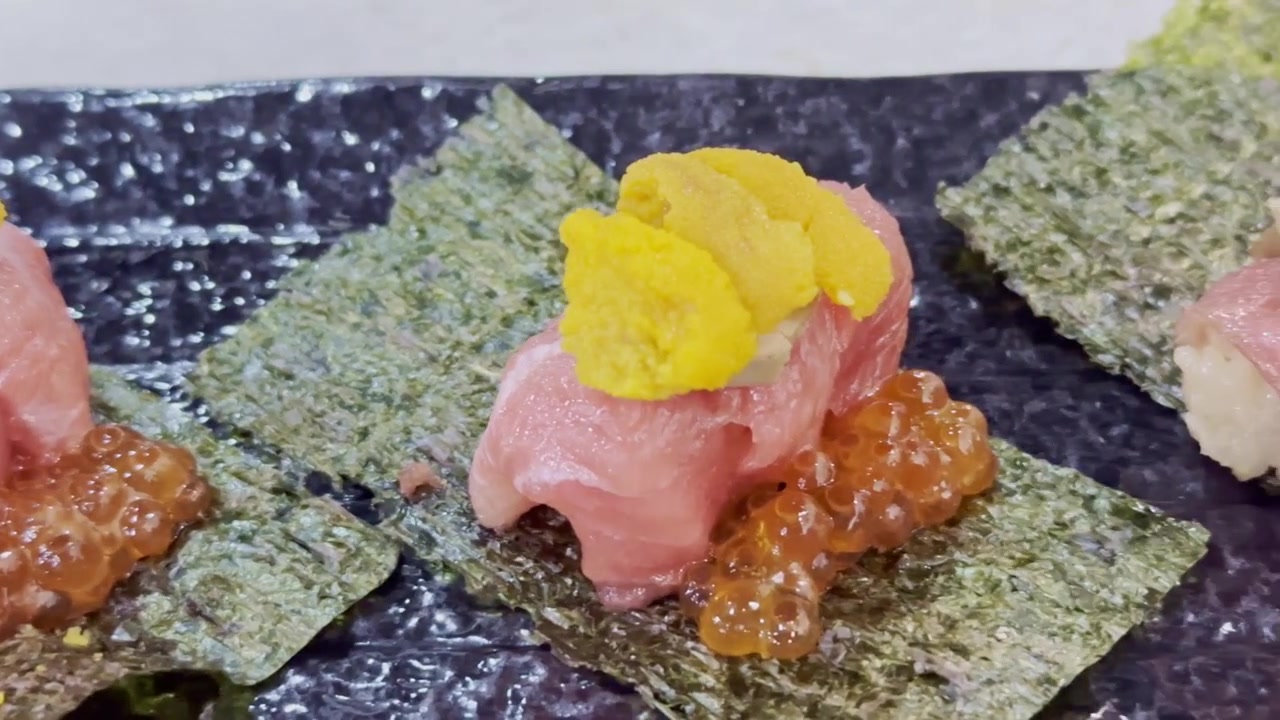 Cận cảnh cuộn otoro cầm tay được cuộn trong rong biển, phủ gan ngỗng cao cấp và nhím biển tươi, thể hiện trải nghiệm ẩm thực Nhật Bản sang trọng, tinh tế