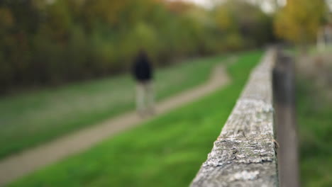 Verschwommener-Mann-Geht-Von-Der-Kamera-Weg-Und-Konzentriert-Sich-Auf-Den-Zaun