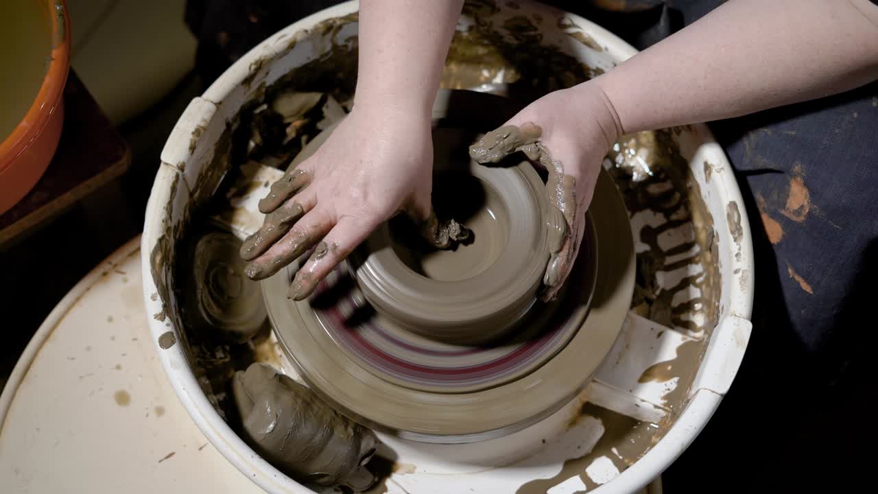 close up shot of the clay ware, the master forms the shape of the pot on the potter's wheel, pieces of clay fly apart