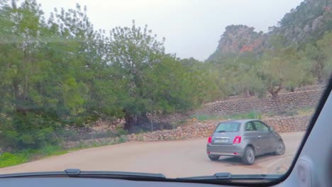 a drive in sant llorenç zigzag road showing traditional mallorcan village greenery, following a car mallorca, spain, captured from car windscreen