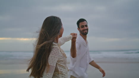 cheerful lovers connecting hands dark beach. loving people ocean date vertically