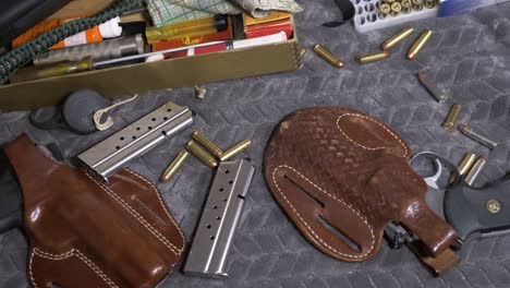 60pslomotion: tiro de arriba hacia abajo inspeccionando varias armas de fuego, pistolas, revólver, rifle, municiones