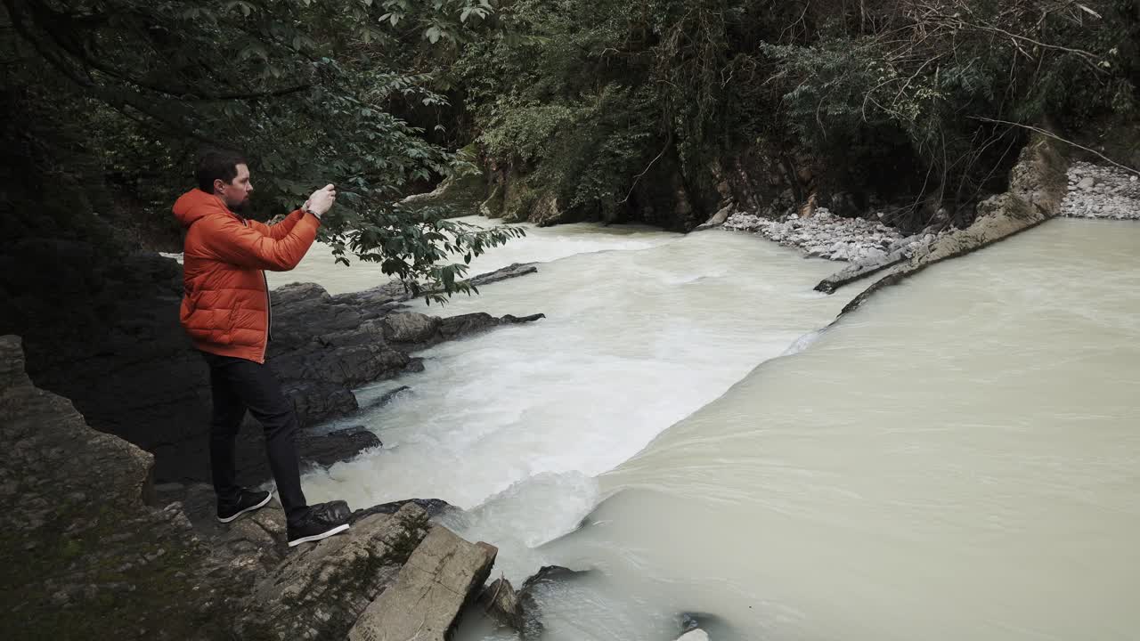 hombre tomando una foto de una cascada en un bosque
