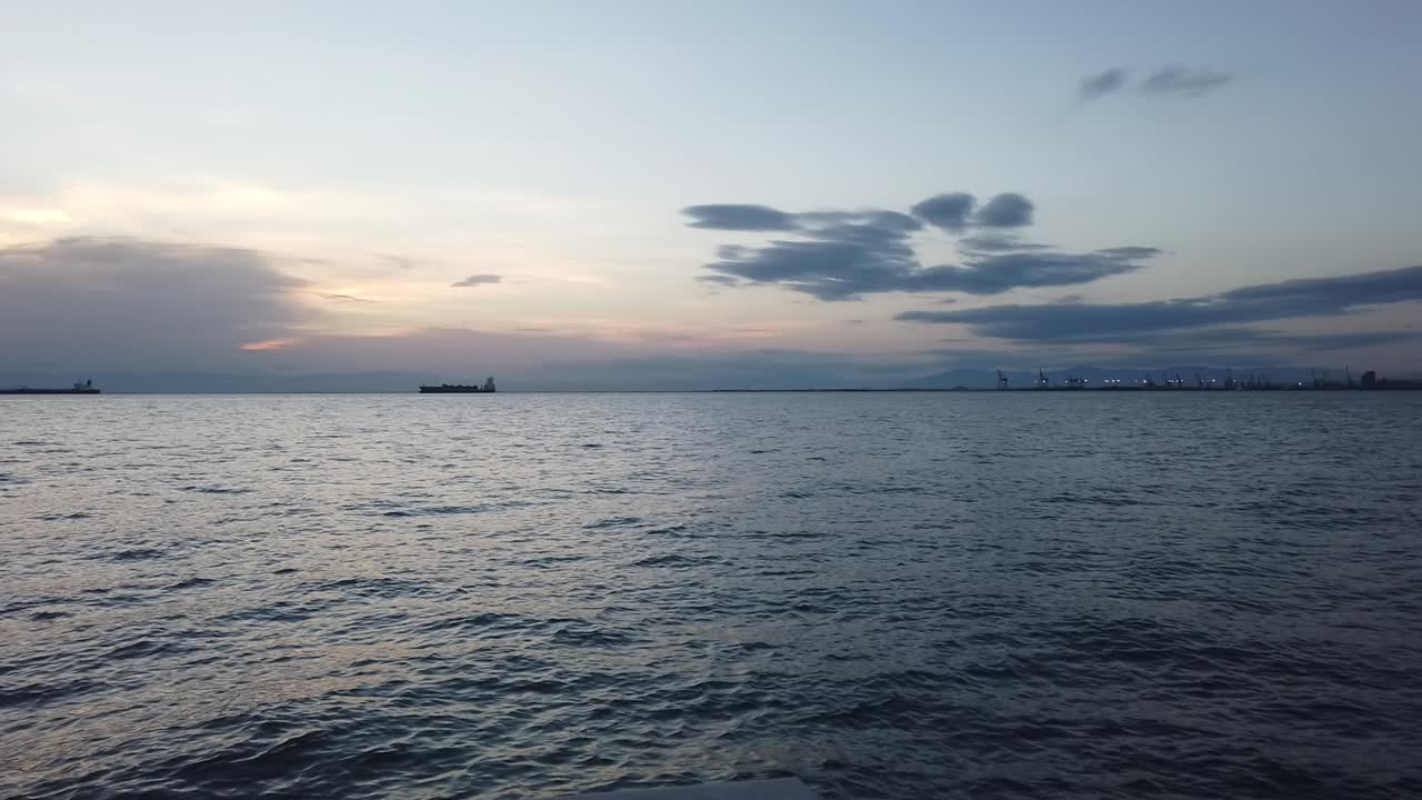 일몰 동안 그리스의 테살로니키 항구에 있는 바다와 화물선의 클립