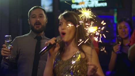 caucasian woman singing and jumping with sparkler