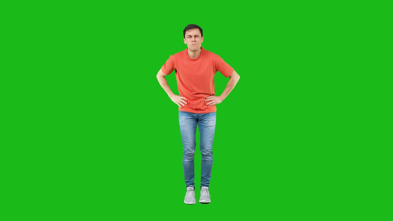 Young man showing confidence and 'I'm watching you' gesture on green screen