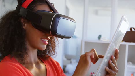 Side-view-of-American-African-female-fashion-designer-using-virtual-reality-headset-and-digital-tabl