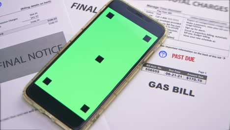 green screen cell phone next to some utility bills that have been marked &quot;past due