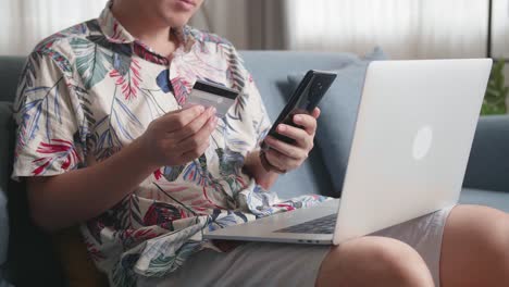 Close Up Of Hand Holding Credit Card And Using Smartphone Shopping Online In Living Room