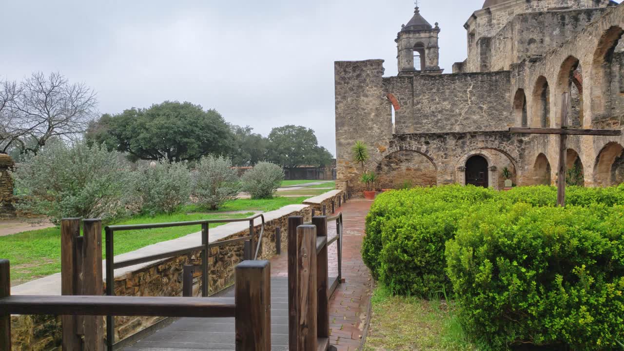 mirando a través de las ruinas de una antigua ventana de piedra de la misión para revelar a un monje en el recinto de la iglesia