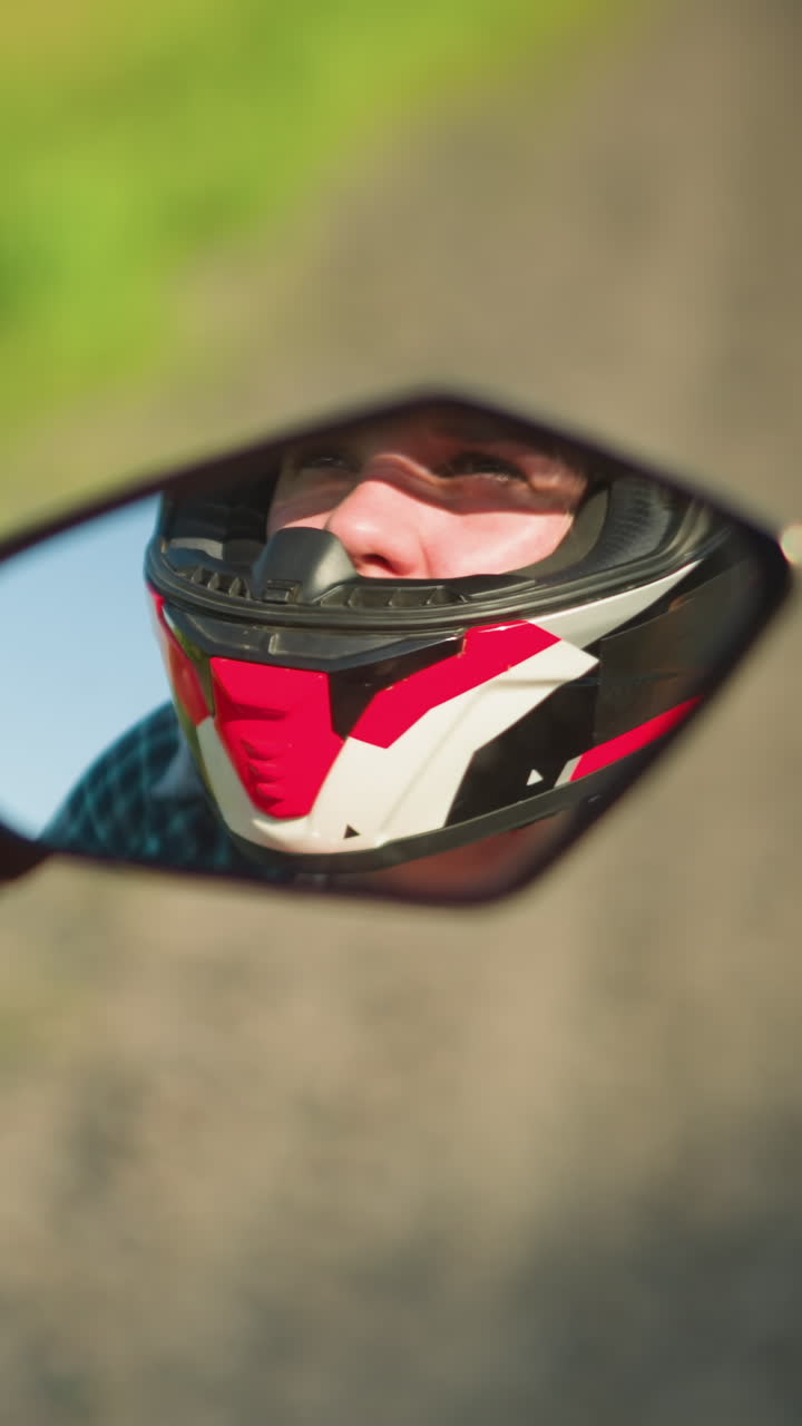 reflejo en primer plano de la cara de un motociclista visto a través del espejo de la motocicleta, con un casco, con un fondo borroso suave