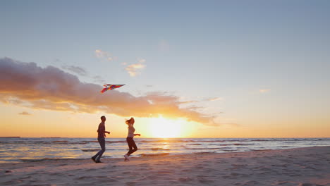 Young-Couple-Playing-With-A-Kite-On-The-Beach-At-Sunset