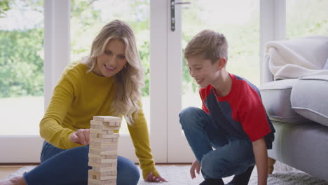 mother and son at home playing game stacking and balancing wooden blocks together