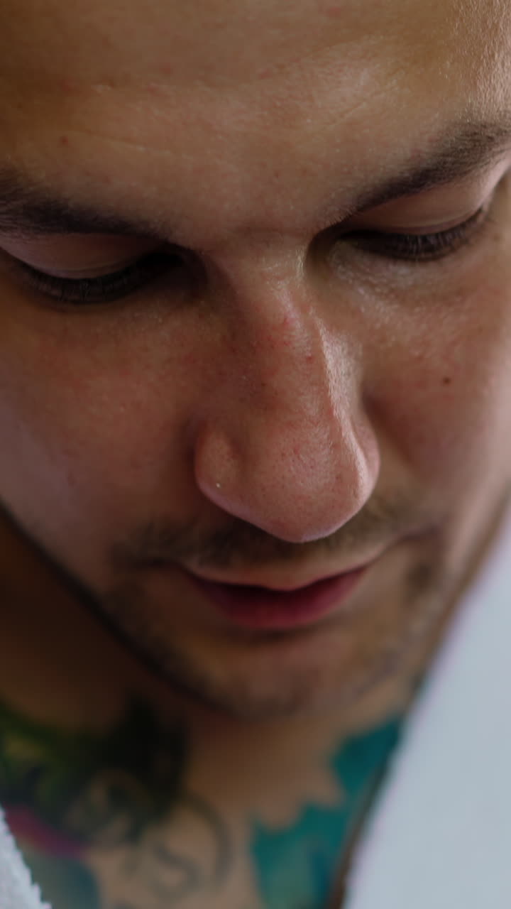 Guy guest with tattoos in white terry gown records audio message talking by mobile phone in hotel room extreme close view slow motion