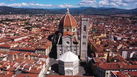 vista aérea de la catedral de santa maria del fiore volando y acercándose con la ciudad y las montañas en un día soleado en florencia en italia en 4k