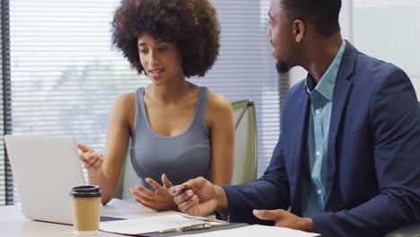 video of happy diverse businessman and female designer working with laptop