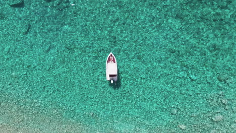 Top-Down-Aerial-View,-Anchored-Boat-by-White-Beach-in-Crystal-Clear-Sea-Water,-Exotic-Travel-Destination-Concept