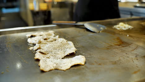 un chef japonés que prepara carne de cerdo frita en rodajas en una estufa caliente para cenar con los clientes en un restaurante de ambiente