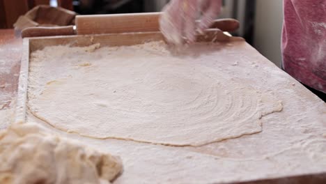 woman, housewife, sprinkles flour on the rolled dough