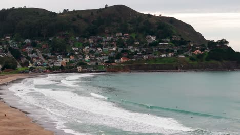 stationary-drone-shot-of-hundreds-of-surfers-on-in-the-ocean-with-waves