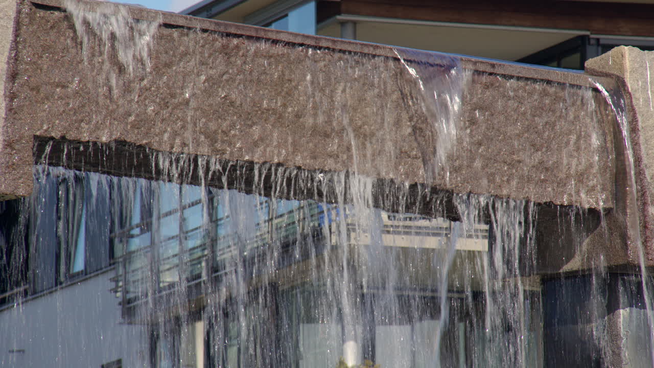 Close up shot of water pouring over the top of the Nupen fontenen at Nupen parken, Kristiansand