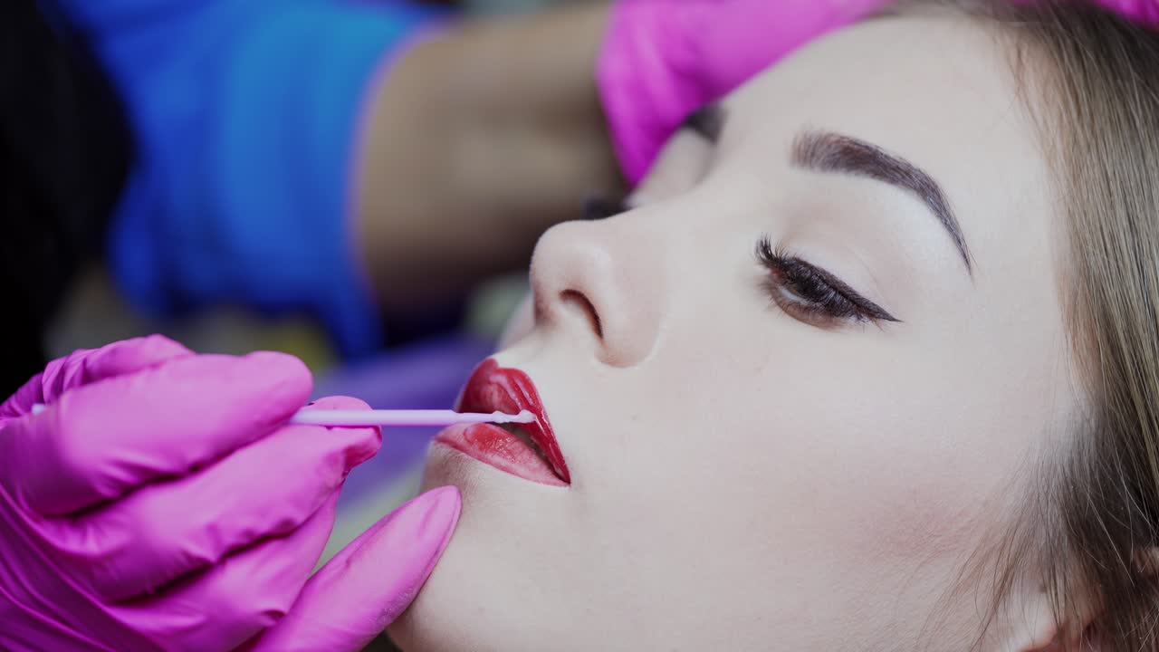 Permanent make up on lips. Young woman having permanent makeup on lips in beautician salon