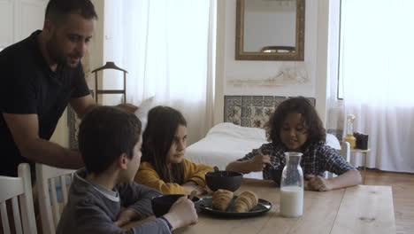 Single-father-pouring-cereal-into-kids-plates-at-breakfast.