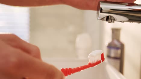 un homme met du dentifrice sur une brosse à dents.