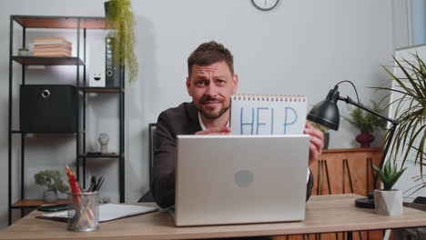 hombre de negocios independiente cansado y sobrecargado de trabajo trabajando en una computadora portátil mostrando un cuaderno de inscripciones con texto de ayuda