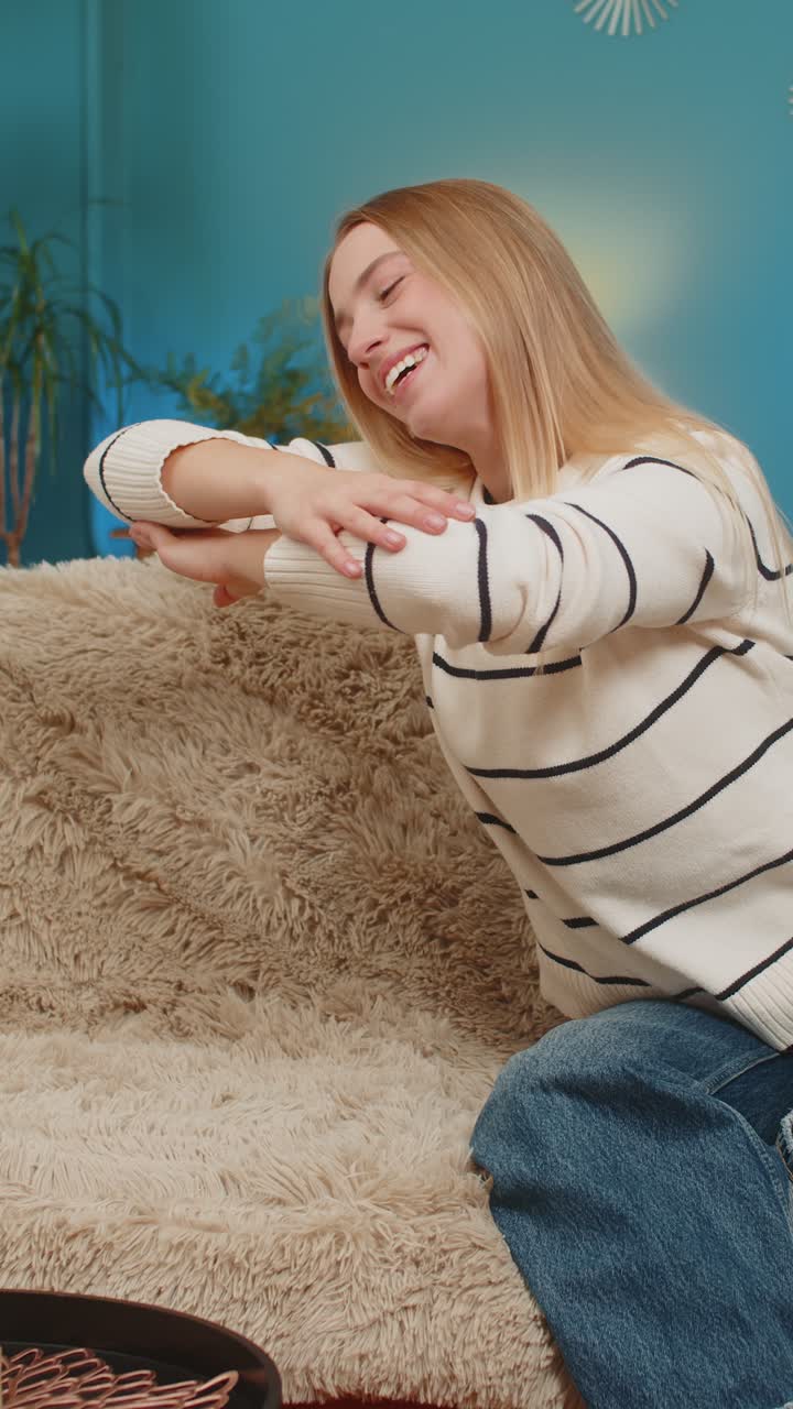 mujer caucásica conversando con un amigo imaginario riendo haciendo un gesto de abrazo en el aire en casa en el sofá