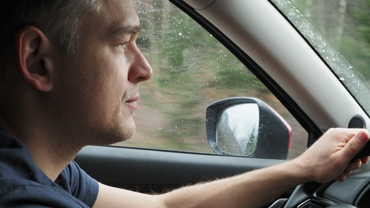 비가 오는 동안 차를 운전하는 남자