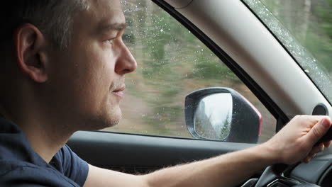 hombre conduciendo un coche bajo la lluvia