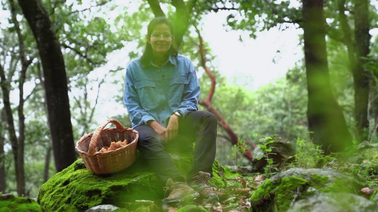 Woman attentively looking at camera with mushroom in woods