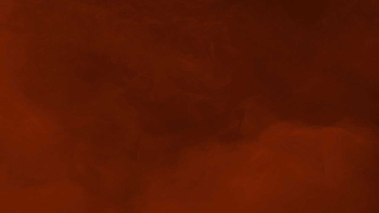 Densa nebbia arancione incandescente e nuvole di fumo nella parte inferiore dello schermo su sfondo nero, loop continuo.