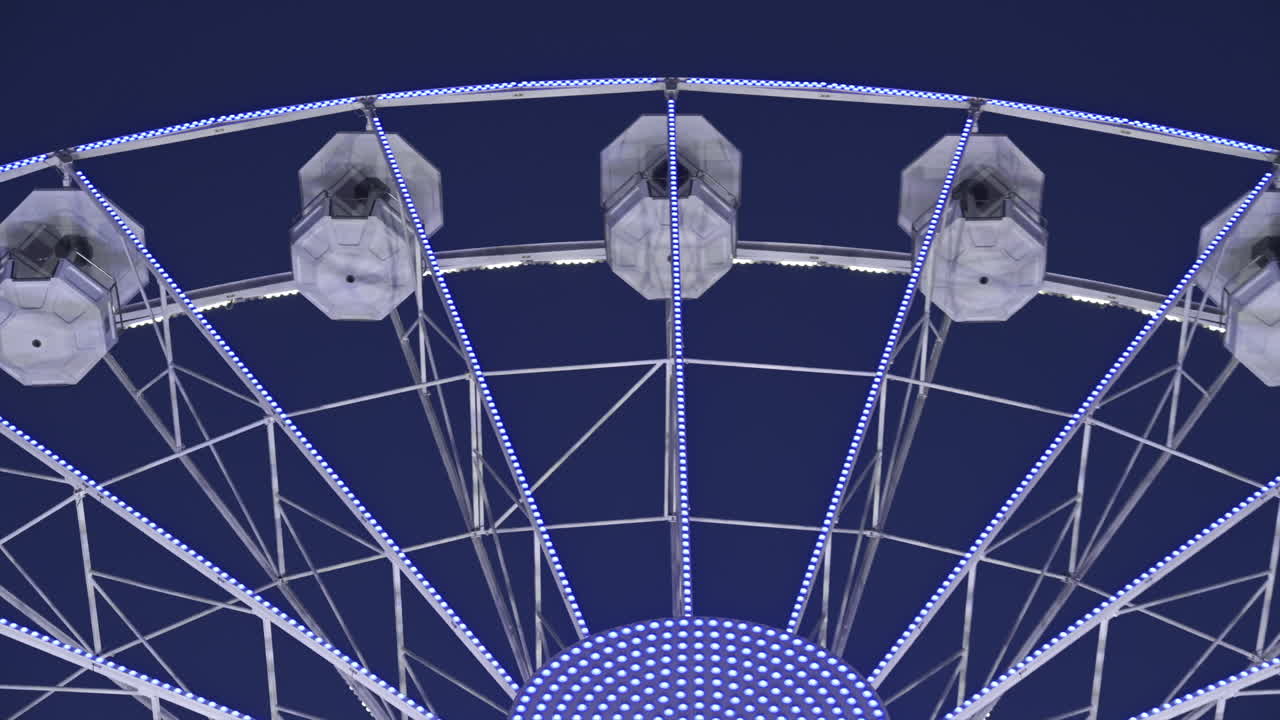 View of white, illuminated ferris wheel rotating in Antibes, France in the evening