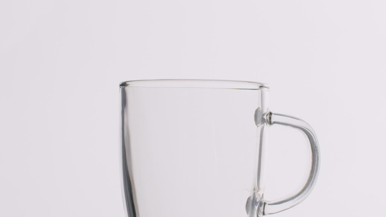 slowmotion은 신선한 커피로 가득 차는 유리 컵의 샷을 닫습니다.