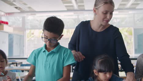 Female-school-teacher-watching-diverse-group-of-pupils-drawing