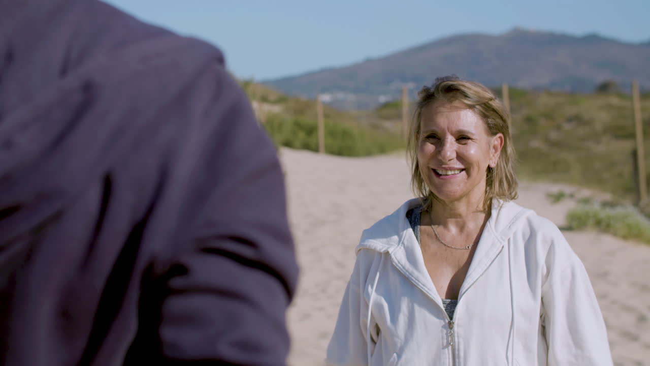 mujer feliz en ropa deportiva estirando los brazos con su marido al aire libre