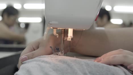 manos operando una máquina de coser, ejemplificando el arte de coser
