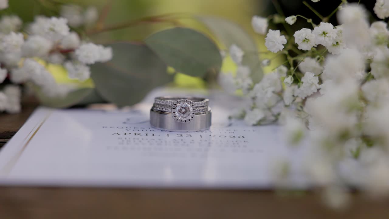 Weddings rings surrounded by babies breath flowers on a wedding invitation
