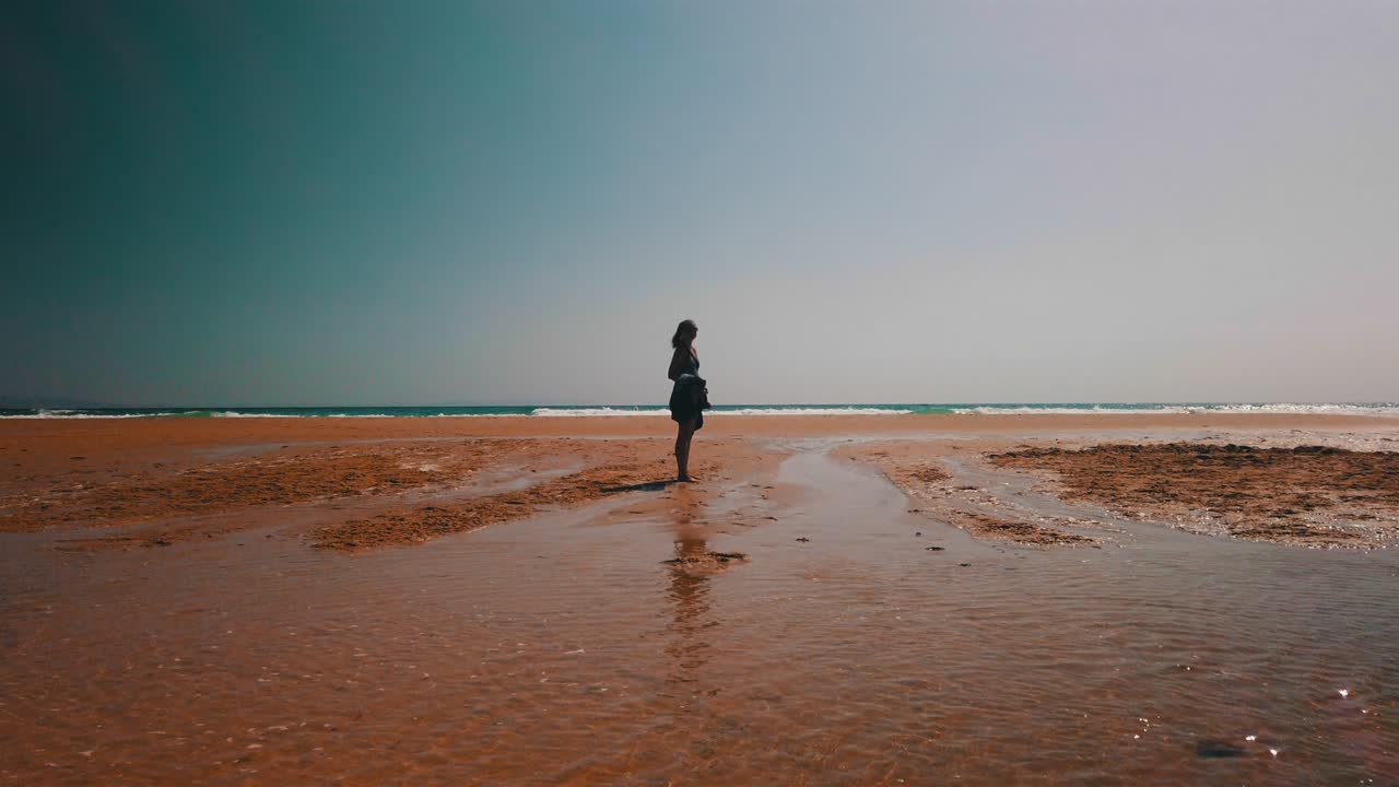 Silhouette di donna che cammina sulla spiaggia al rallentatore in 4k