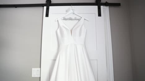 bride's wedding dress hanging up on a hanger on her wedding day