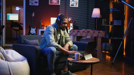 vertical video focused black guy teleworking on laptop in a living room feels happy