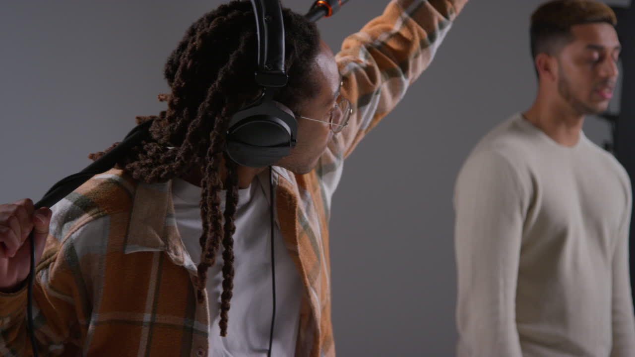 grabador de sonido de película masculino con auriculares sosteniendo el micrófono el poste de grabación del boom el actor filmando una película o video en el estudio filmado en tiempo real 1