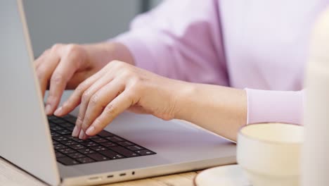 mano de cerca de una mujer de negocios escribiendo teclado computadora portátil en la oficina de escritorio