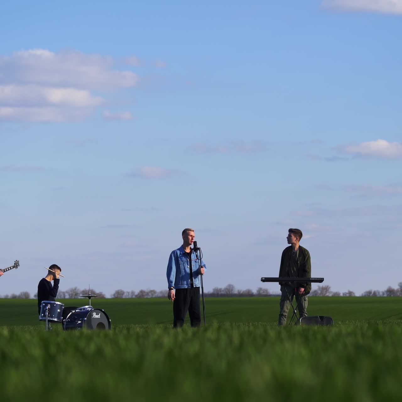 Four musicians performing their energetic music in the plantations. Young men create music, sing and move actively. Nature backdrop