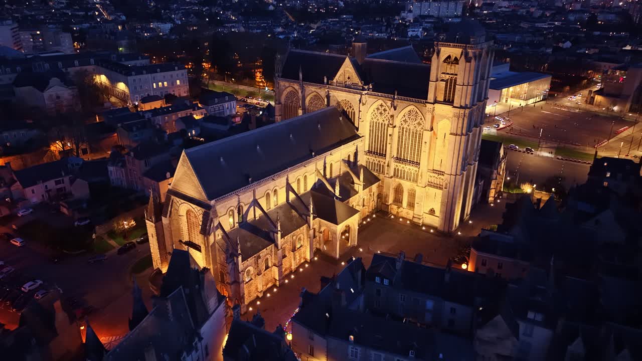 Ampla foto aérea da iluminada Cathédrale Saint-Julien e da histórica cidade antiga de Le Mans à noite, França. Drone voando para trás