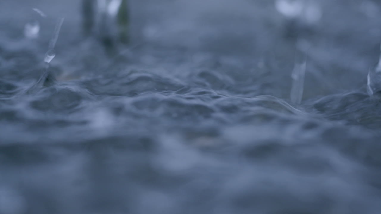 cámara lenta de gotas de lluvia salpicando en un charco durante una tormenta tropical que causa inundaciones