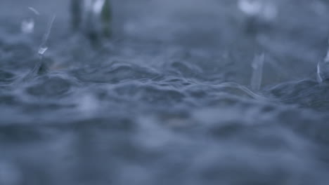 Slow-mo-of-rain-droplets-splashing-in-a-puddle-during-a-tropical-storm-causing-flooding